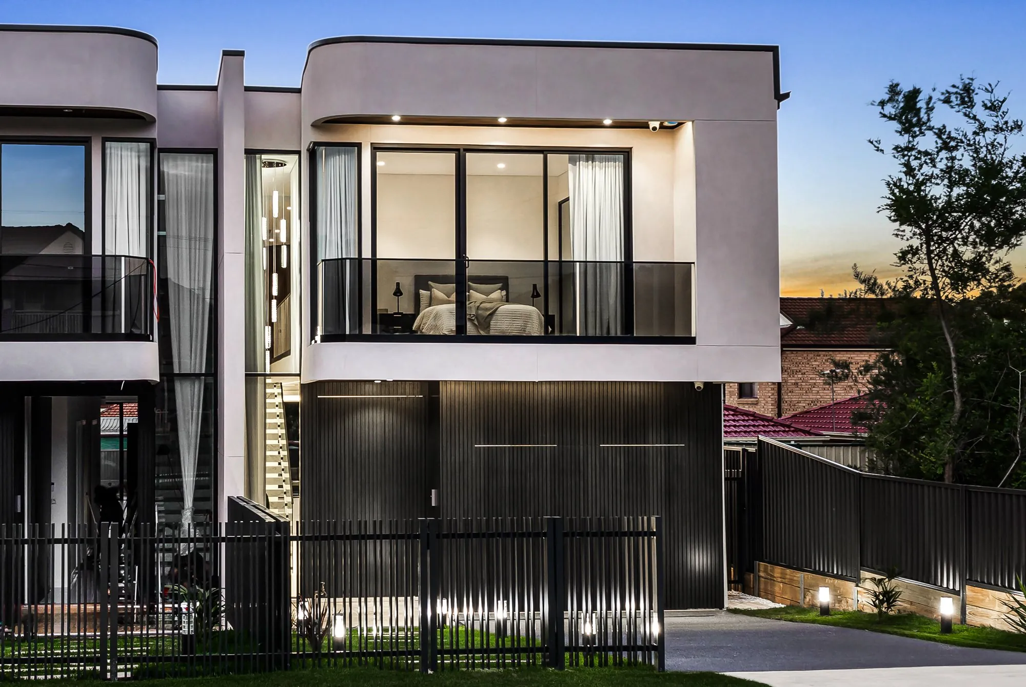 Two-storey duplex at dusk with landscaped front garden